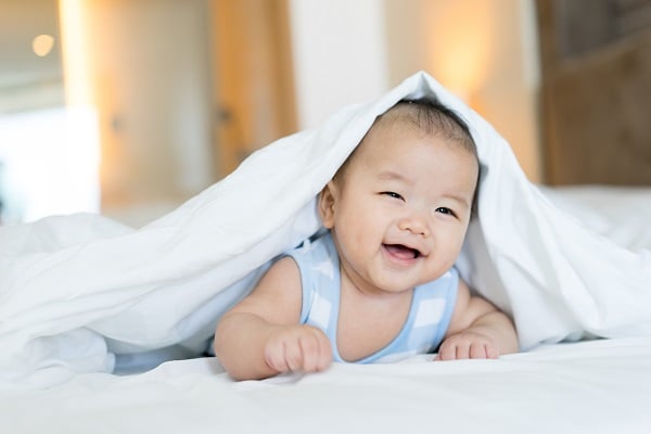 a cute baby peaking his head out from under a blank