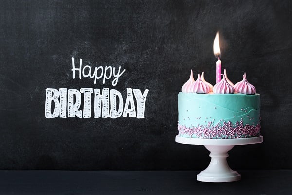 Teal colored birthday cake with one candle. the words on a chalkboard: Happy Birthday