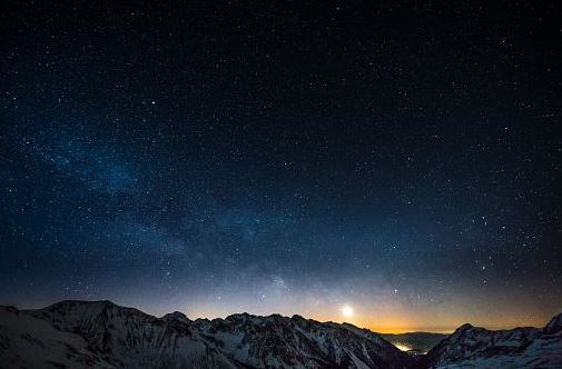 An image of the night sky full of stars over mountains