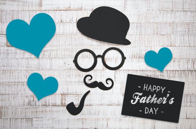black Cutouts of a hat glasses and pipe against a white brick wall. The card reads Happy Father's Day.