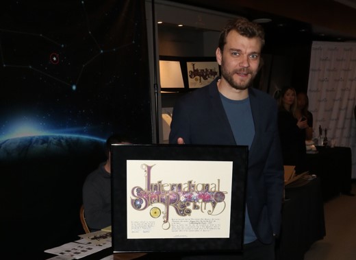 Pilou Asbaek holding his name a star certificate from starregistry.com