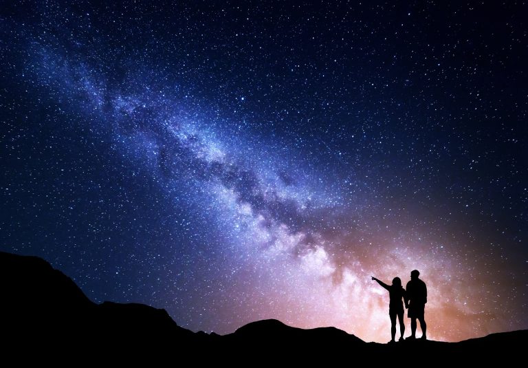 Couple pointing toward a star in the Milky Way