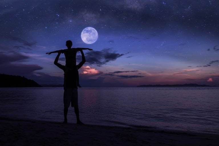 parent with child on shoulders looking at the moon