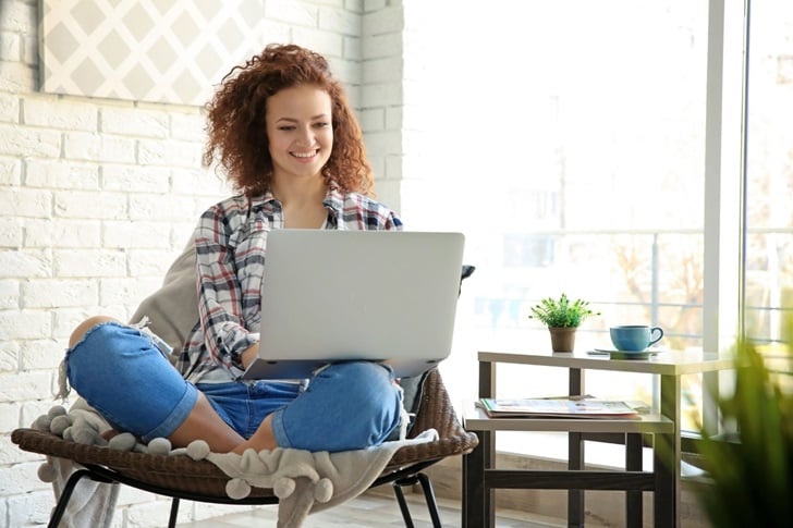 Woman with curly red hair sitting in a chair buying a star with her a laptop from International Star Registry