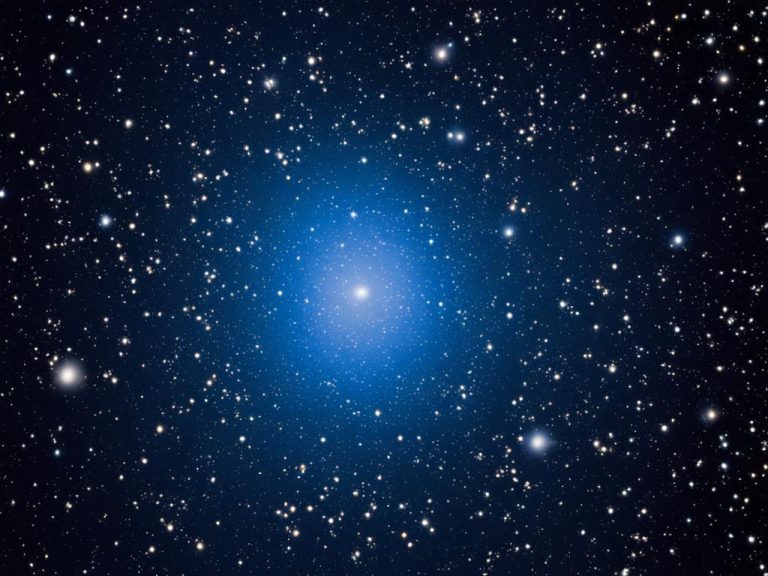 A beautiful dark blue night sky full of stars is accented by a single bright star surrounded by bright blue light.