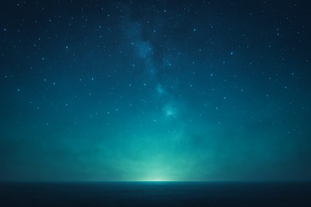 A view looking toward a light on the horizon. Above is a sky filled with stars