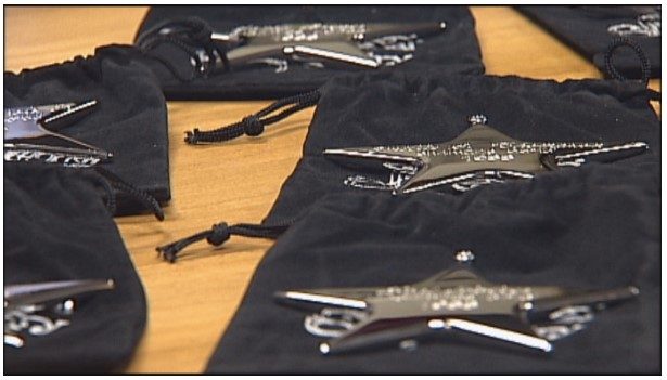 Silver Christmas ornaments displayed across a table on black velvet bags.