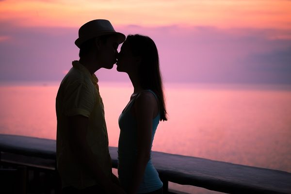 Couple kissing at the sunset over the ocean.