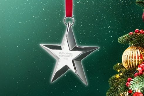 Sterling silver star ornament suspended by a red ribbon. The name and coordinates of a named star are engraved on the ornament