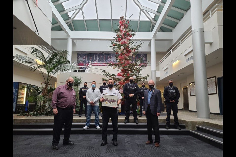 richmond-rcmp-and-rcrg Image of police holding an International Star Registry certificate in front of a Christmas tree.