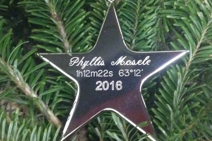Star shaped ornament in Christmas tree has star name and coordinates